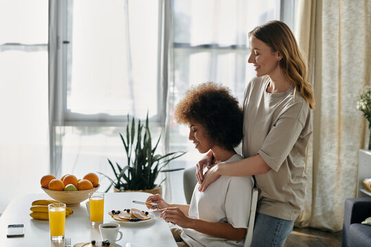 A diverse lesbian couple shares a tender moment while enjoying breakfast at home.
