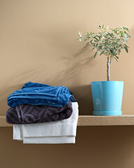 colored towels near the laundry basket on a bright background and an olive tree