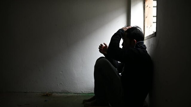 Asian man addict drug in the deserted place,A junkie feels alone in this world,Sad young man sitting in the corner of the room,People are stressed and have depression