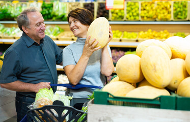 Fototapeta premium Elderly husband and wife choose high-quality melon