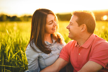 couple standing and hugging before a kiss against the background of the sunset in the field