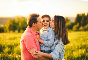Beautiful father and mother with son on sunset field