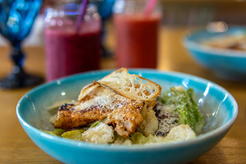 Caesar salad in blue plate. Salad and smoothies in the cafe. Soft focus