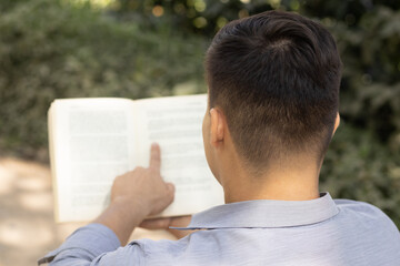 latin young man reading a book in nature