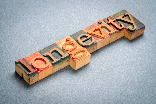 longevity text in retro letterpress wood type stained by color inks, lifespan and aging concept