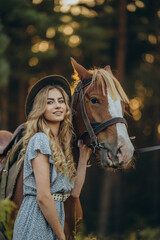 Obraz premium A young beautiful woman walks with her horse in the forest in early autumn. Walking with a horse in the forest.