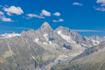 Tour du Montblanc beautiful mountain ladscapes of the Alps green valley, snow summit of Montblanc and rocky peaks of Aiguille du Midi in summer sunny weather blue sky, trekking and hiking in Chamonix