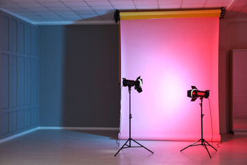 Photo background in neon lights and professional lighting equipment inside modern studio, space for...