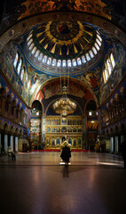 Obraz premium Old woman prays on her knees in the middle of Holy Trinity Orthodox Cathedral of Sibiu, Transylvania, Romania