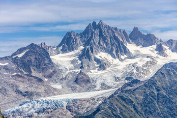 Tour du Montblanc beautiful mountain ladscapes of the Alps green valley, snow summit of Montblanc and rocky peaks of Aiguille du Midi in summer sunny weather blue sky, trekking and hiking in Chamonix