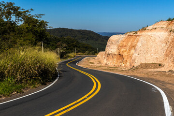 View of an empty paved rural road, flanked by Atlantic forest and eucalyptus fields in a mountain range in Brazil