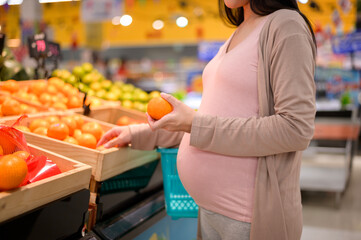 Beautiful pregnant woman shopping healthy food at grocery shop