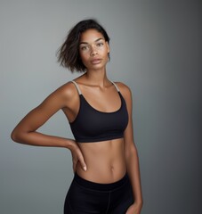 Fototapeta premium Young slim athletic brunette on a gray background. Active lifestyle, weight loss, motivation.