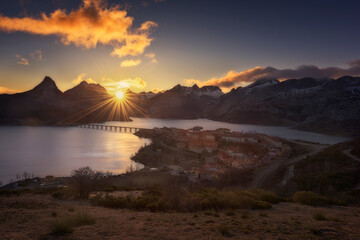 Sunset over the Riaño reservoir with the sun in front setting between the mountains in the...