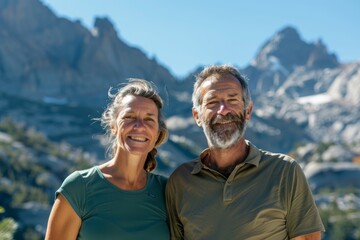 Portrait of a joyful couple in their 40s sporting a breathable hiking shirt in front of backdrop of mountain peaks