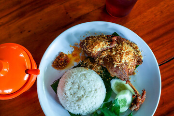 Crispy Fried Duck with Rice, Vegetables, Spicy Sambal, and Sweet Iced Tea