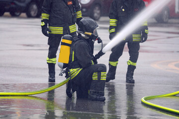 Firefighters with oxygen tanks and breathing apparatus wearing protective helmets and foam...