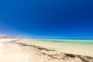 Krajobraz morski, piaszczysta plaża i wybrzeże, żółty piasek, widok na lazurowe morze, niebieski kolor nieba, wyspa Djerba, Tunezja. Tapeta, egzotyczne tło