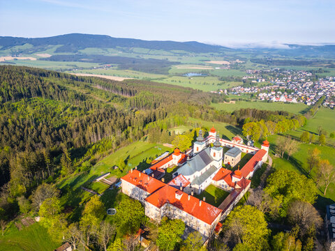 An aerial view of Hora Matky Bozi Monastery, located in Dolni Hedec near Kraliky, Czechia. The monastery is surrounded by lush greenery and a scenic landscape.