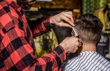 Hipster client getting haircut. Hands of barber with hair clipper. Haircut concept. Hairstylist...