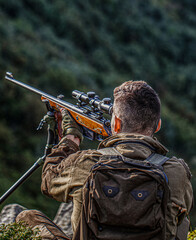 Hunter with hunting gun and hunting form to hunt. Hunter is aiming. Shooter sighting in the target....