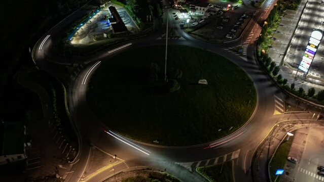 Aerial drone hyperlapse of a traffic roundabout in a city at night.