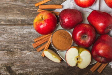 Apples with cinnamon on a textured wooden background. Fragrant red spiced apples with cinnamon sticks and star anise. Apple slices with spicy spices. Place for text. Copy space. Harvesting. Fruits.
