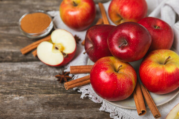 Apples with cinnamon on a textured wooden background. Fragrant red spiced apples with cinnamon sticks and star anise. Apple slices with spicy spices. Place for text. Copy space. Harvesting. Fruits.