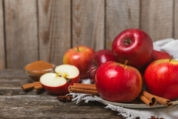 Apples with cinnamon on a textured wooden background. Fragrant red spiced apples with cinnamon sticks and star anise. Apple slices with spicy spices. Place for text. Copy space. Harvesting. Fruits.