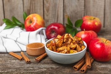 Apples with cinnamon on a textured wooden background. Fragrant red spiced apples with cinnamon sticks and star anise. Apple slices with spicy spices. Place for text. Copy space. Harvesting. Fruits.