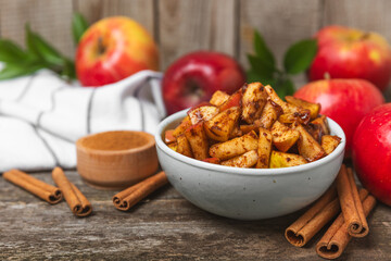 Apples with cinnamon on a textured wooden background. Fragrant red spiced apples with cinnamon sticks and star anise. Apple slices with spicy spices. Place for text. Copy space. Harvesting. Fruits.