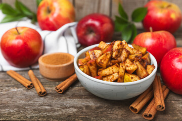 Apples with cinnamon on a textured wooden background. Fragrant red spiced apples with cinnamon sticks and star anise. Apple slices with spicy spices. Place for text. Copy space. Harvesting. Fruits.