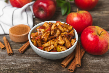 Apples with cinnamon on a textured wooden background. Fragrant red spiced apples with cinnamon sticks and star anise. Apple slices with spicy spices. Place for text. Copy space. Harvesting. Fruits.