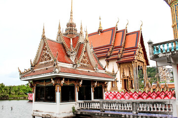 A Thai temple along the riverbank showcases intricate roofs, embodying Thai tradition and culture