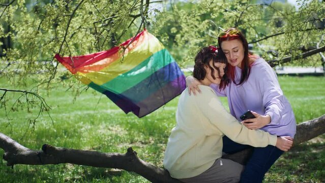 Lgbt community community concept in the park lgbt couple hugging lovely each other and looking over the smartphone together