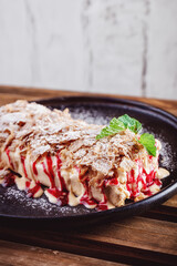 Puff pastry layered napoleon cake. Dessert with juicy vanilla cream and cherry raspberry filling, crumble served on a plate on table in restaurant cafe. Restaurant dish. Specialty coffee aesthetics