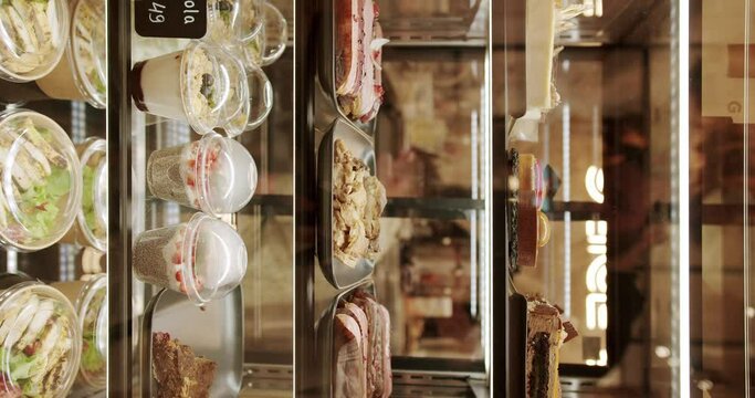 Glass counter with a variety of colorful pastries and desserts. Vertical video. In the coffee and pastry bar. Cakes and sweets in the window of a confectionery restaurant.