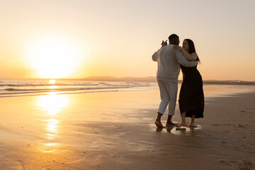 A couple dancing on the beach at sunset