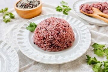 Cooked riceberry on white plate and white blackground with spoon and fork , riceberry it is a very useful rice, top view food table
