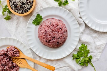 Cooked riceberry on white plate and white blackground with spoon and fork , riceberry it is a very useful rice, top view food table