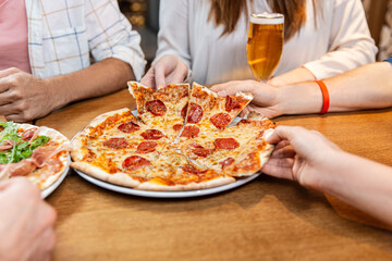 leisure, food and drinks, people and holidays concept - close up of friends eating pizza and drinking beer at restaurant or pub