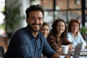 Fototapeta premium Man smiling at table with laptop and others