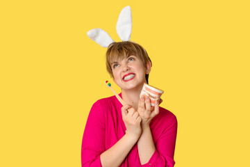A young woman in bunny ears with an amazing smile with a toothbrush and a jaw model in her hands on...
