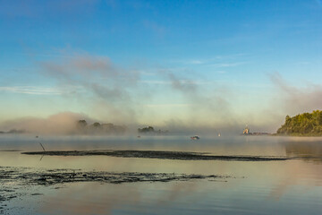 Fishermen on  boats early in the morning at dawn in the fog or mist at golden hour catch fish on...