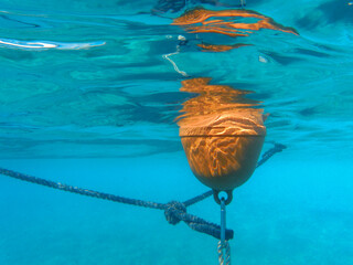 UNDERWATER. Orange floating buoy in the sea for beach marking.