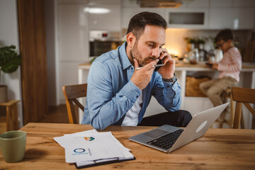 man work from home with son at background and talk on mobile phone