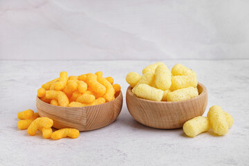 Wooden bowls with different tasty salty corn sticks on light background