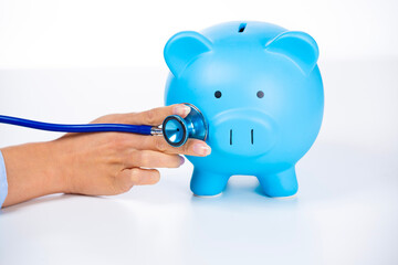 Businesswoman with stethoscope listening to piggy bank
