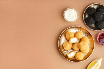 Plates with different delicious fried mozzarella balls and sauces on beige background