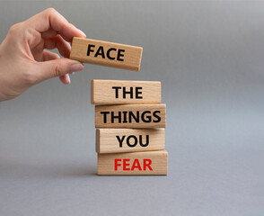 Face the things you fear symbol. Wooden blocks with words Face the things you fear. Beautiful grey background. Businessman hand. Business and Face the things you fear concept. Copy space.